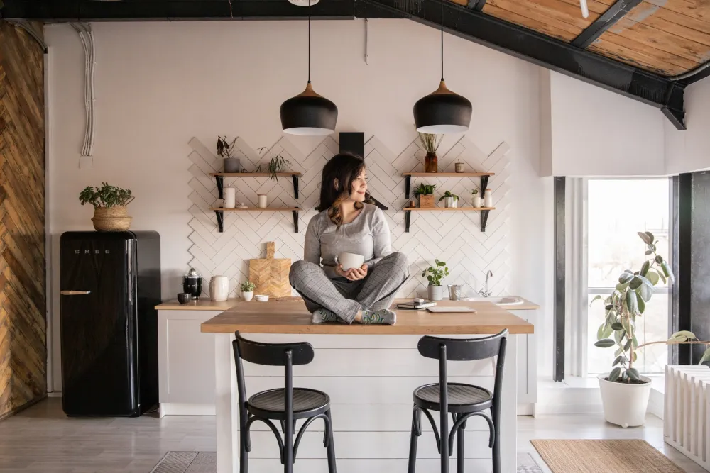 Vrouw die op het aanrecht van de keuken zit